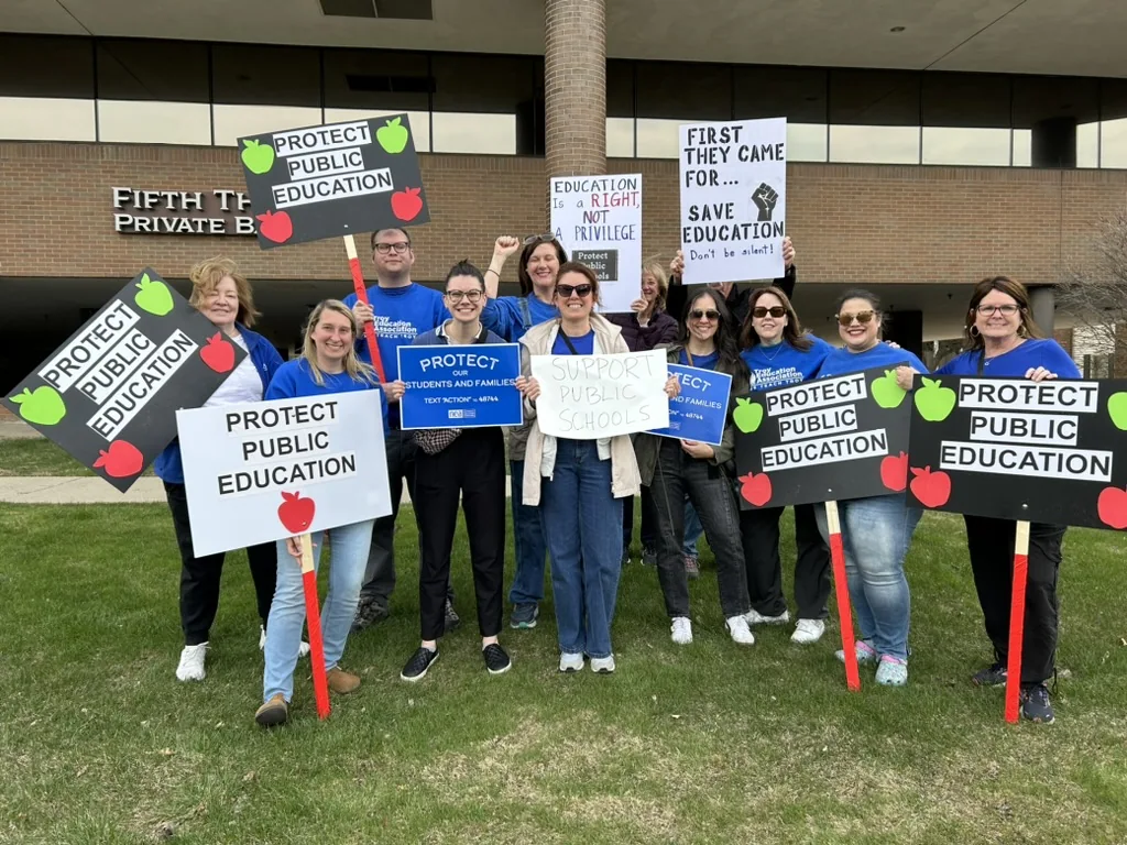 Educators gathering outside with signs supporting public education