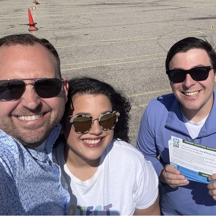 Three people in sunglasses at a Yes for Oakland Kids campaign event