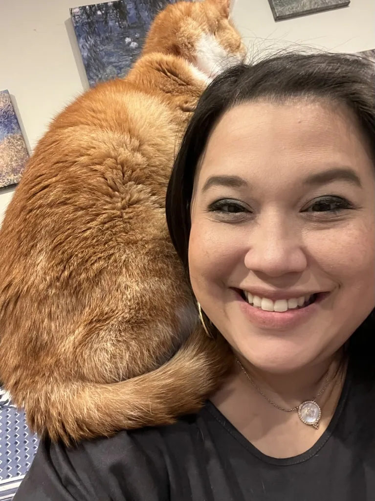 Missy and an orange cat resting across her shoulders