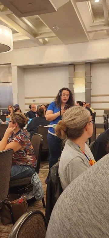 Missy Dodge addressing a group using a microphone at an education conference